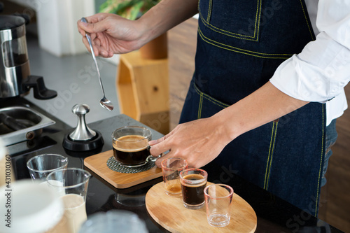 Young Barista preparing and making espresso with coffee machine. Barista making cappuccino in a coffee shop. Barista holding portafilter tamping and preparing cup of coffee.