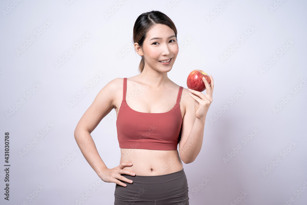Smiling Asian woman in a pink shirt holds a red apple, Isolated on a white background. Smiling Asian woman in a pink shirt holds a red apple, Isolated on a white background.