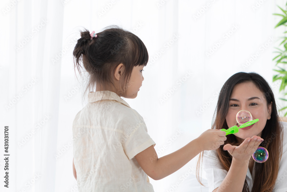 Mother and daughter are playing together on the bed in the morning. Mother and daughter sitting on bed enjoy quality time playing game together during home quarantine. Mother and daughter are playing together on the bed in the morning. Mother and daughter sitting on bed enjoy quality time playing game together during home quarantine.