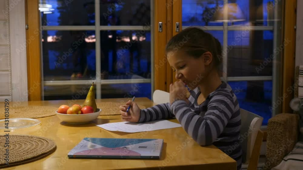 Pretty school girl at home, writing a homework. Child sitting at table and write a letter with pen. Pretty school girl at home, writing a homework. Child sitting at table and write a letter with pen.