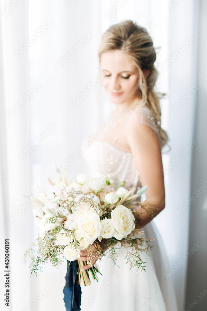 Delicate portrait of the bride with soft focus. A woman holds a wedding bouquet of roses and gypsophila in her hands. Floristry and flowers during the holidays. Wedding decor concept in light color. Delicate portrait of the bride with soft focus. A woman holds a wedding bouquet of roses and gypsophila in her hands. Floristry and flowers during the holidays. Wedding decor concept in light color.