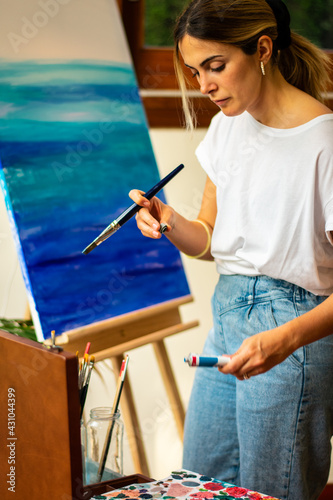 woman painting on easel taking a virtual class