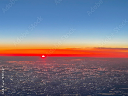 High altitude aerial view of sunrise over the Bering Sea between Alaska and Russia showing ice melting on the surface of the water.