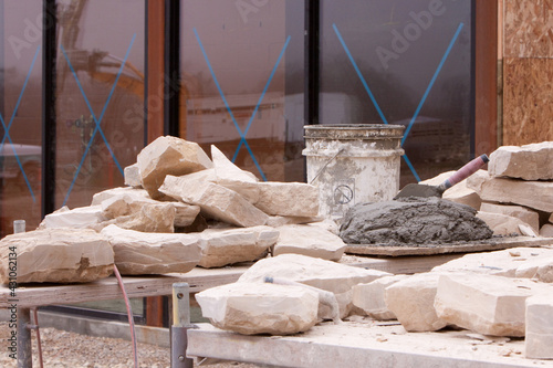 Stones, bucket, trowel, and mortar for masonry work on wall building. 
