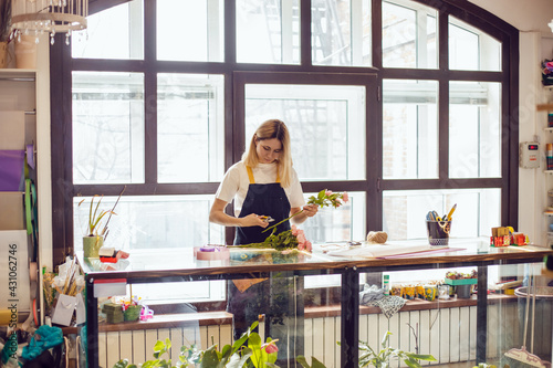 Girl florist collects a composition of flowers in a flower shop.