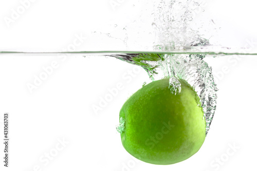 one green apple falling into water on a white background with splashes, drops and bubbles