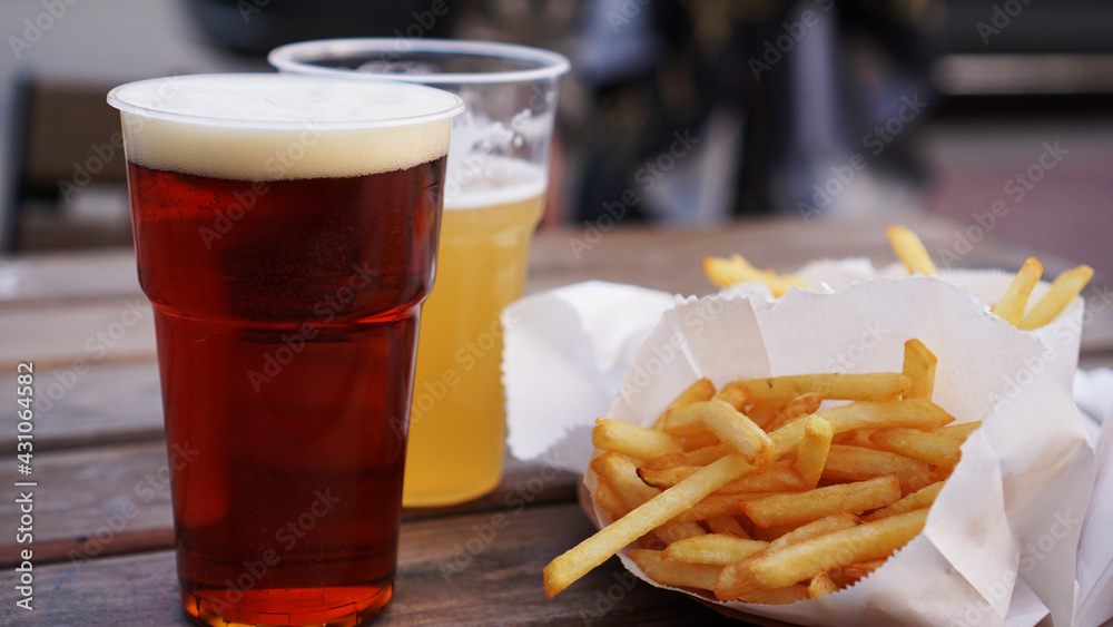 Dark and light beer and fries on a wooden table. Food court. Takeaway food, food festival. Unhealthy food concept