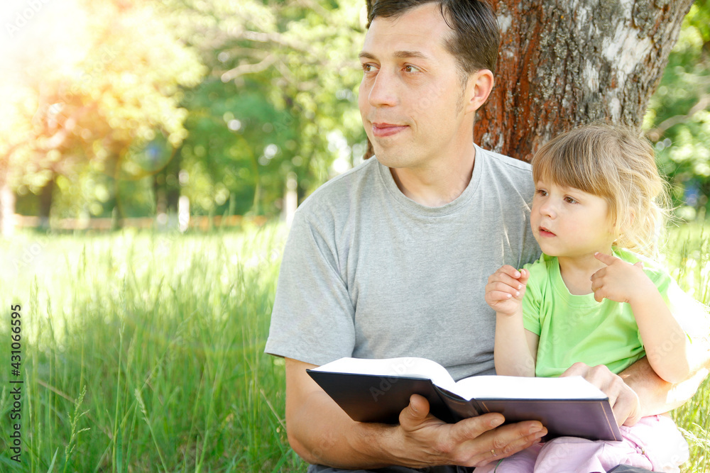 happy father with a child reading a book on the nature of the Bible happy father with a child reading a book on the nature of the Bible