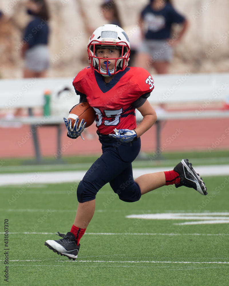 Fototapeta premium Young athletic boy playing in a youth tackle football game