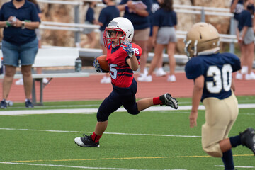 Young athletic boy playing in a youth tackle football game