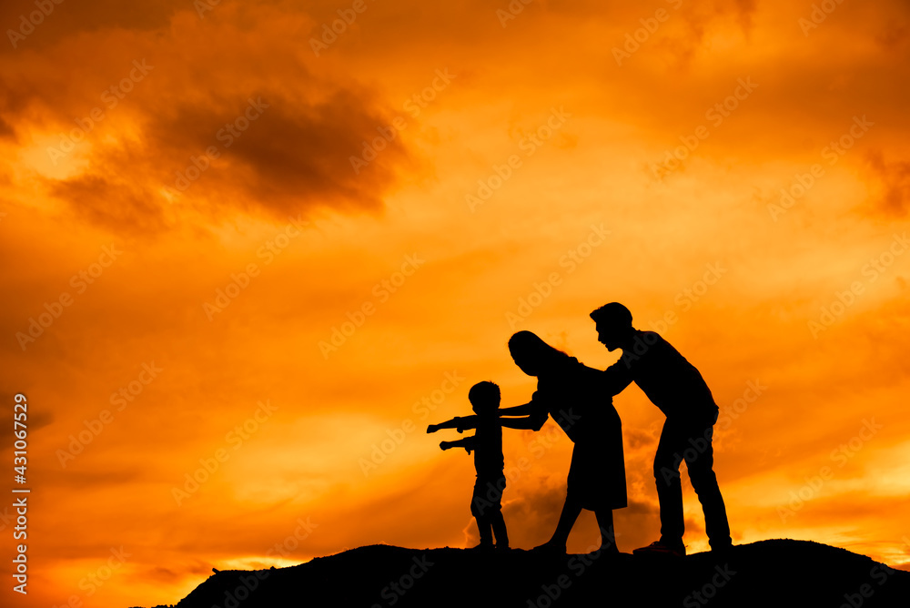 silhouette of happy family father mother and son playing outdoors at sunset.