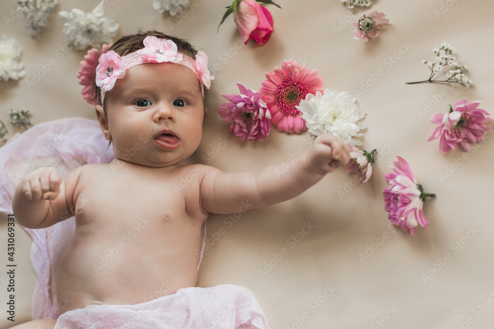 Newborn baby in a wreath of flowers. Lying on the bed with flowers. Naked. On a light background. Newborn baby in a wreath of flowers. Lying on the bed with flowers. Naked. On a light background.