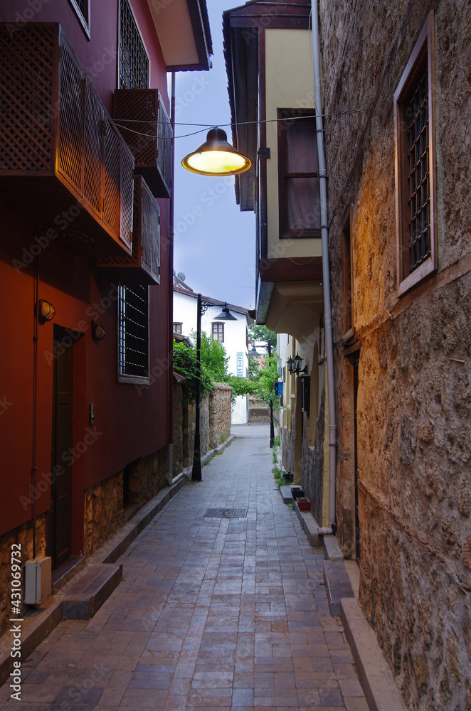 Narrow street with old buildings and a lantern in the evening.