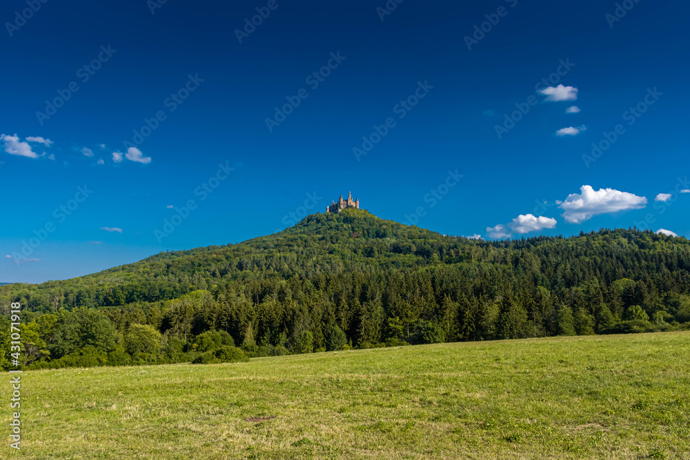 Fototapeta premium Aerial view of famous Hohenzollern Castle, ancestral seat of the imperial House of Hohenzollern and one of Europe's most visited castles, on the top of a green hill in Baden-Wurttemberg, Germany