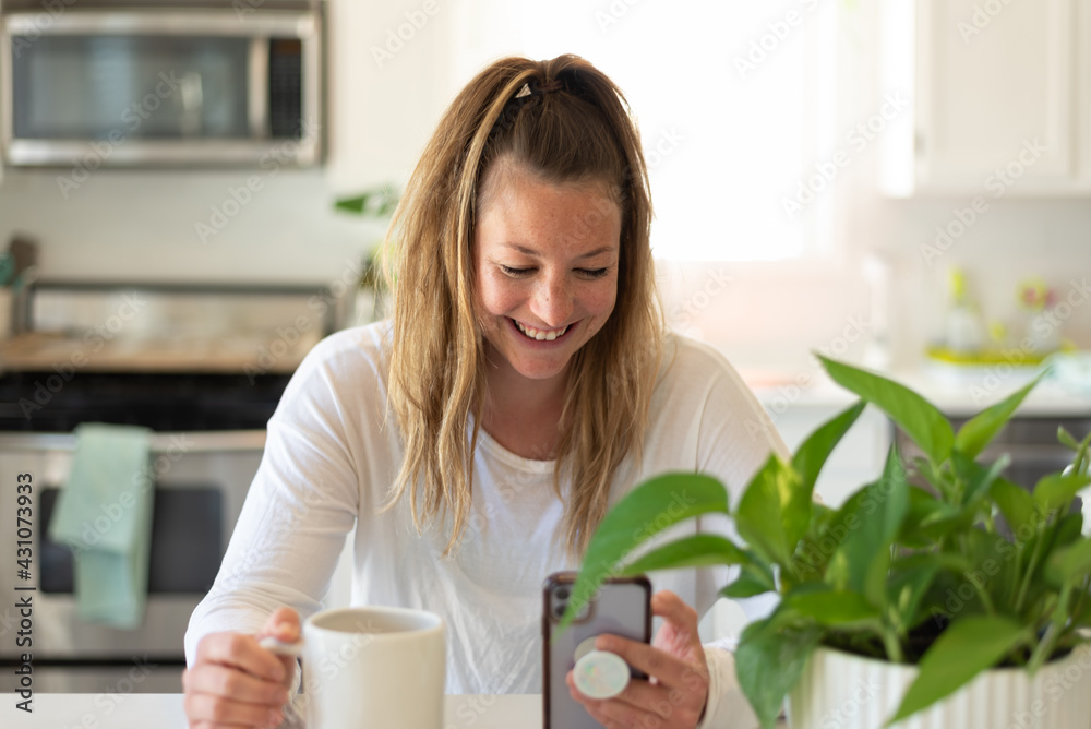 Young woman with coffee and phone in the kitchen Young woman with coffee and phone in the kitchen