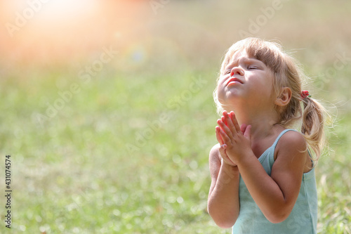 happy clittle girl praying in nature photo