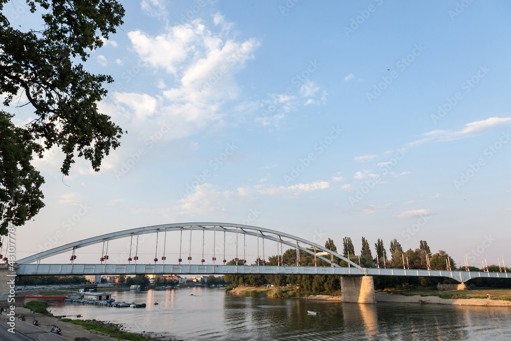 Obraz premium Belvarosi Hid bridge, also known as Downtown bridge on the tisza river during a sunny sunset. The bridge connects the two parts of this city, the main one of Southern Hungary.