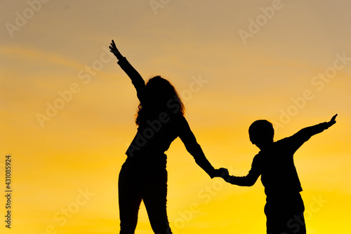 Silhouettes of woman and boy doing physical exercises at sunset.