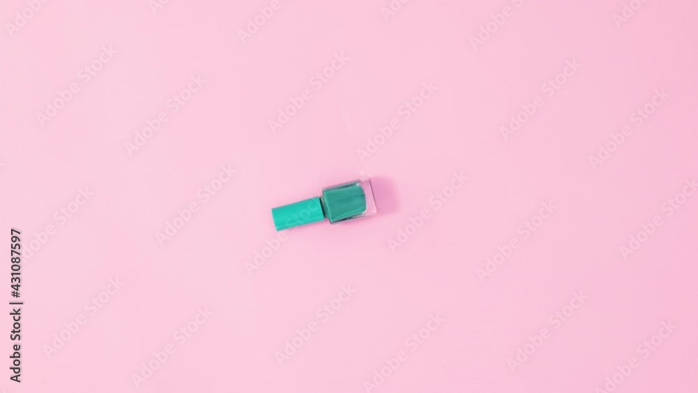 Manicure cyan pink nail polish bottle rotating on pastel pink background. Stop motion flat lay Manicure cyan pink nail polish bottle rotating on pastel pink background. Stop motion flat lay