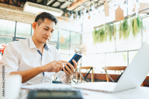 young businessman working and using smart phone and notebook computer in workplace.