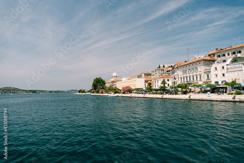 Ancient houses against the background of blue sky and azure sea on the embankment of Sibenik, Croatia