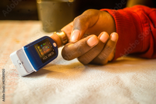 Closeup shot of a pulse oximeter on a black woman's finger to measure pulse rate and oxygen levels photo
