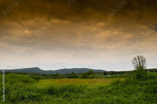 landscape view with blue black red sky and green mountain.