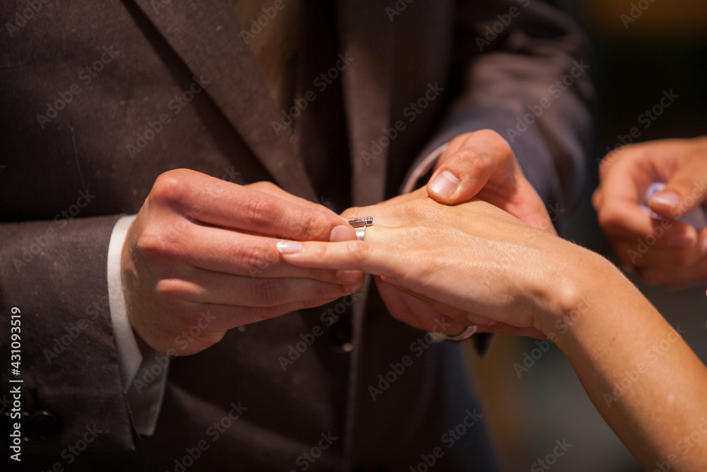 Closeup of bride putting a wedding ring onto the groom's finger. Couple exchanging wedding rings. High quality photo