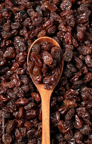 Wooden spoon on top of a grape-raisin in the background photo