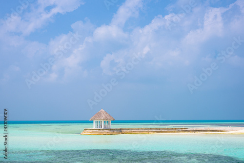 A small gazebo on a Maldivian island surrounded by clear turquoise water