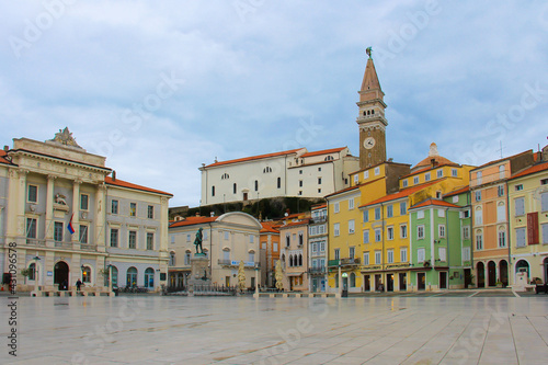 The Tartini square of Piran with colorful houses, shops, cafes, a monument and a town hall is empty after the rain.