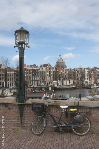 Vertical shot of a bicycle parked on a bridge in the beautiful city of Amsterdam during dayli photo