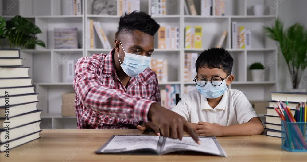 Young african teaching asian boy during quarantine at home Young african teaching asian boy during quarantine at home