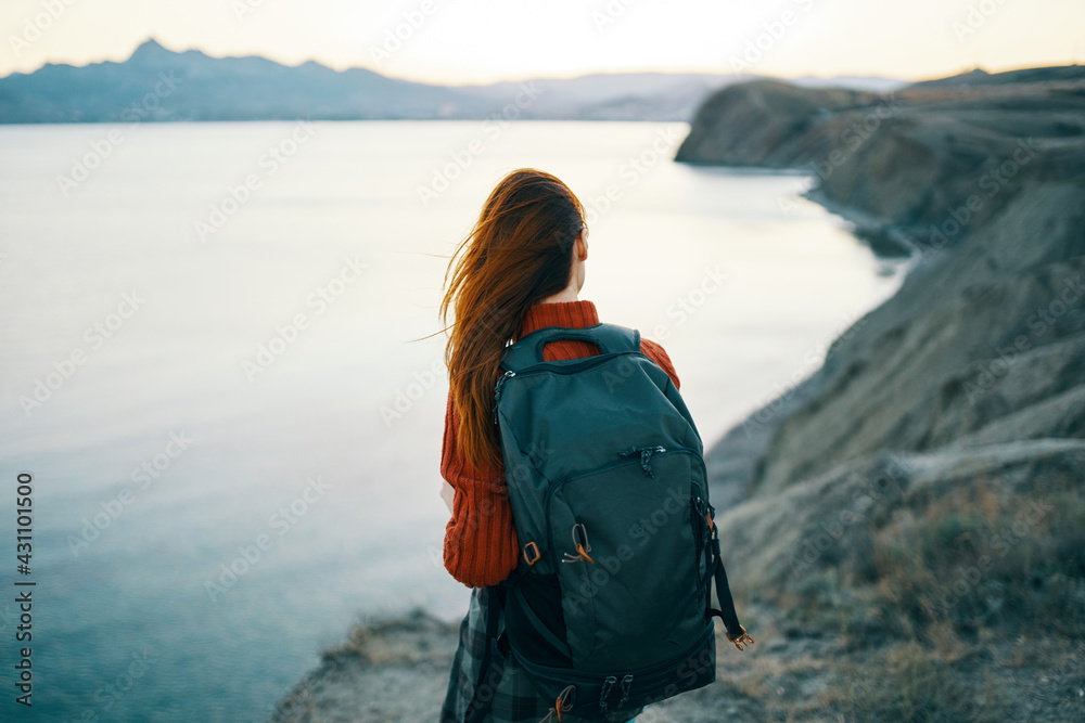 a traveler with a backpack on her back looks at the sea in the distant mountains landscape ocean clear water a traveler with a backpack on her back looks at the sea in the distant mountains landscape ocean clear water