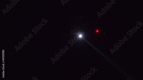 A police helicopter hovers and uses its spotlight during the hunt for a crime suspect at night.
