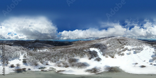 360 degrees photo of the beech forest of the Nebrodi mountains in Sicily during a light snowfall in early spring. View of Etna. Monte Soro and the Aeolian Islands with the Tyrrhenian Sea. 