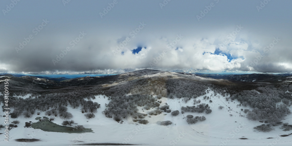 360 degrees photo of the beech forest of the Nebrodi mountains in Sicily during a light snowfall in early spring. View of Etna. Monte Soro and the Aeolian Islands with the Tyrrhenian Sea. 360 degrees photo of the beech forest of the Nebrodi mountains in Sicily during a light snowfall in early spring. View of Etna. Monte Soro and the Aeolian Islands with the Tyrrhenian Sea.