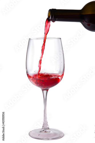 Red wine is poured into a glass from a bottle, isolate on a white background
