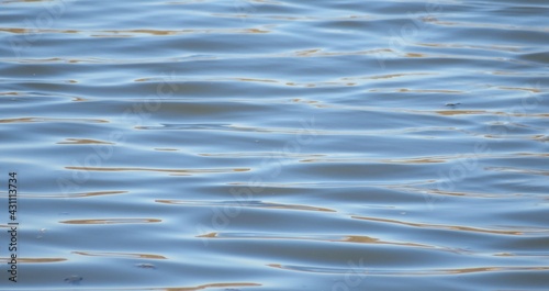 Blue water background with ripples and sun glare