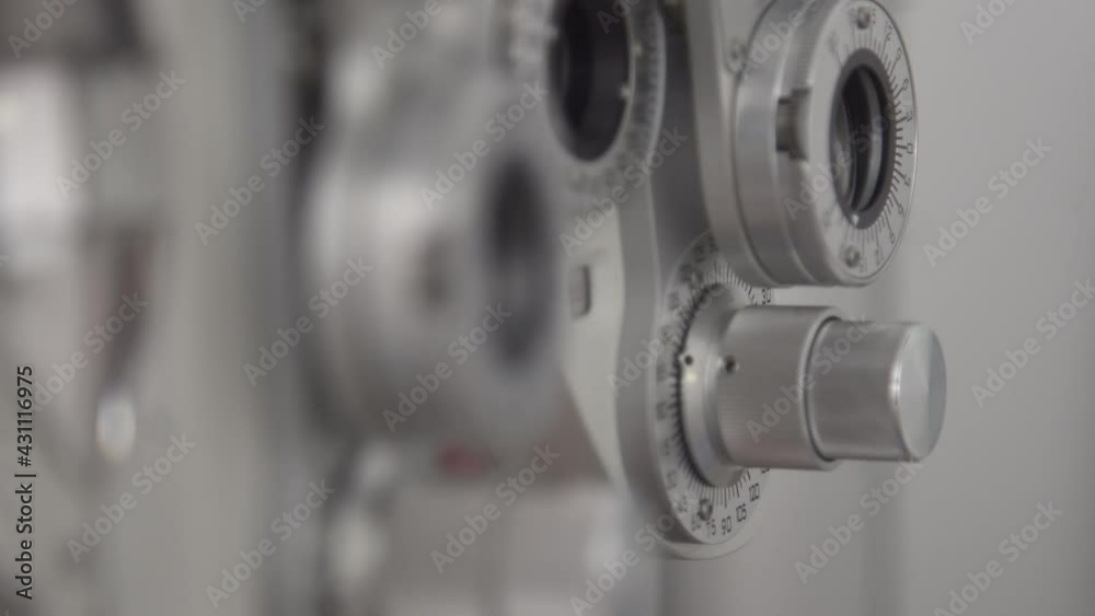 Close up the ophthalmologist fine-tunes the optics of the Phoropter equipment. Close up the ophthalmologist fine-tunes the optics of the Phoropter equipment.