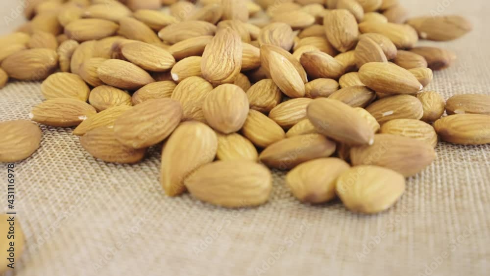 Close up almonds seed rotate on brown fabric, Slow motion almond kernels rotation with brick background, Front view almond nuts rotating, Concept whole grains of food for healthy. Close up almonds seed rotate on brown fabric, Slow motion almond kernels rotation with brick background, Front view almond nuts rotating, Concept whole grains of food for healthy.