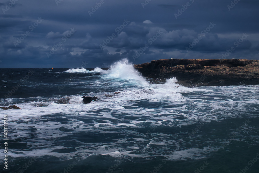 Waves crashing over the rocks on a stormy day in Qawra, Malta.
