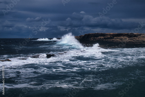 Waves crashing over the rocks on a stormy day in Qawra, Malta.