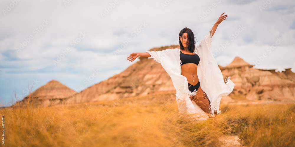 Young brunette Caucasian girl in a white dress and a black bikini enjoying in the beautiful desert Young brunette Caucasian girl in a white dress and a black bikini enjoying in the beautiful desert