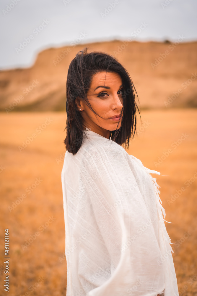 Portrait of a brunette Caucasian model girl in a white dress and a black bikini in a desert one summer afternoon, vertical photo Portrait of a brunette Caucasian model girl in a white dress and a black bikini in a desert one summer afternoon, vertical photo
