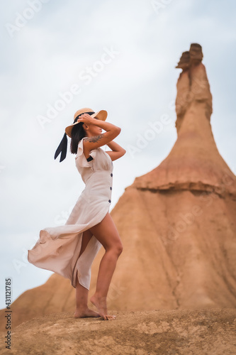 Brunette Caucasian model with a white dress and a straw hat in the Castildetierra of the Bardenas Reales desert, Navarra. Spain