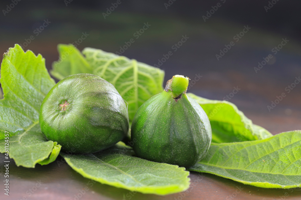 Green leaves, fresh small figs on the wooden background.