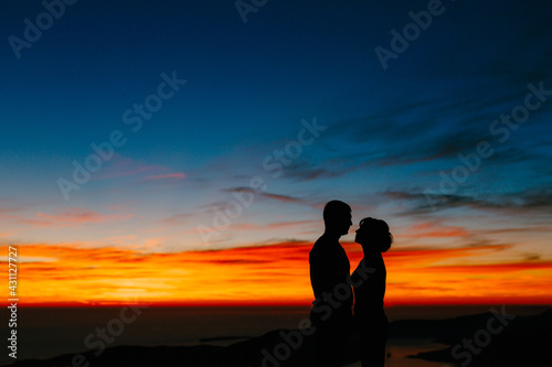 Silhouettes of a couple holding hands against the background of the sunset in the mountains. Close up