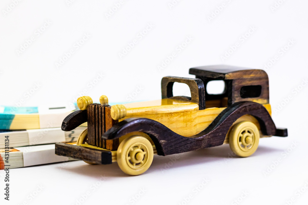 Close up shot of a wooden vintage car toy with money notes behind, showing rich concept.
