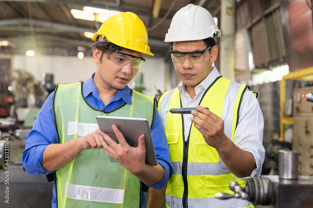 Technicians and engineers are comparing parts of the spare parts to the samples from Tablet in industrial plants Technicians and engineers are comparing parts of the spare parts to the samples from Tablet in industrial plants